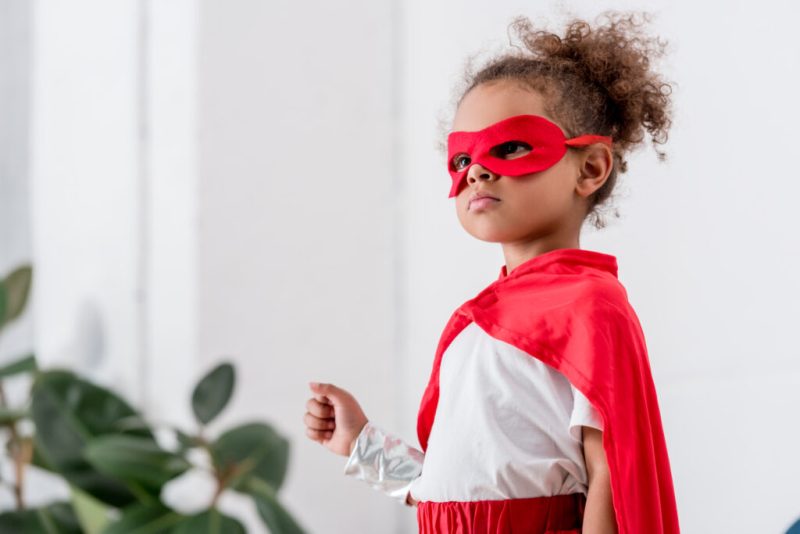 Portrait of cute little african american child in red superhero costume and mask